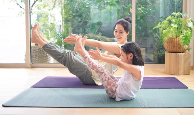 床にシートを敷いて、ヨガを楽しむ母子。